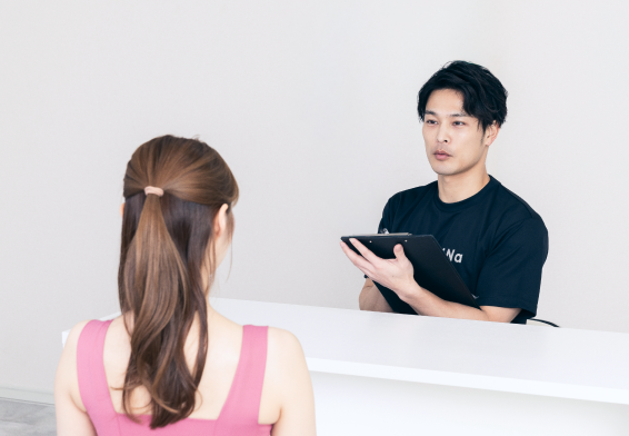 受付でカウンセリングを行うReViNaのトレーナーとお客様